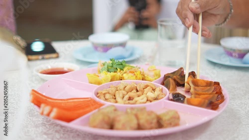 4K Close-up of hand using chopsticks to pick up century egg from colorful Chinese appetizer platter on banquet table, Traditional party catering festive dining and asian food concept.