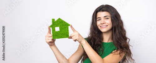 Happy house buyer. A young girl holds a model of a green house in her hands. The concept of green energy, ecology.