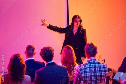 Fotografie Female presenter pointing at blank screen during business seminar