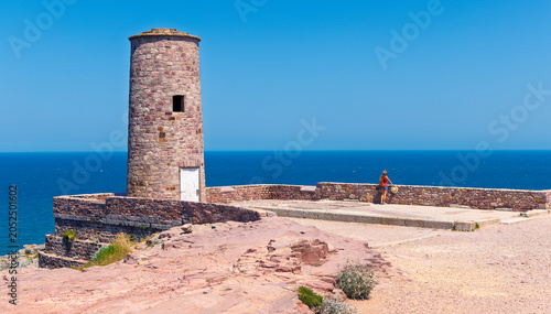 Принти на полотні Woman traveler standing by the historic pink sandstone foghorn tower at Cap d'Er