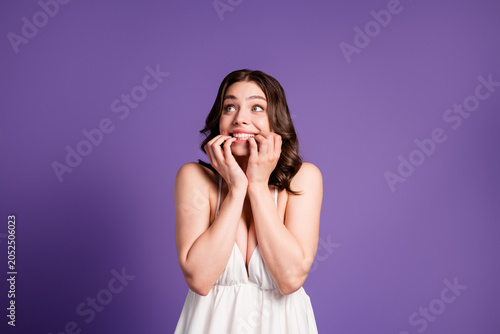 Принти на полотні Nervous young woman biting her nails in a white dress against a purple backgroun