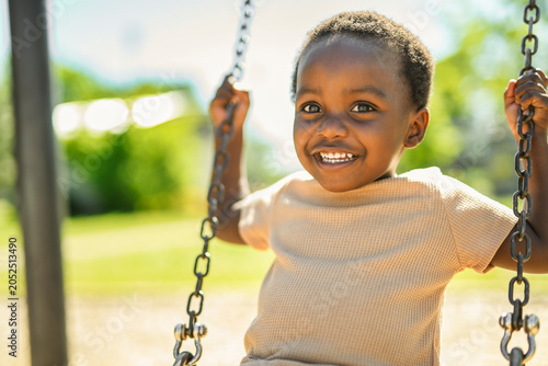 Happy young american child on playground swing this summer season