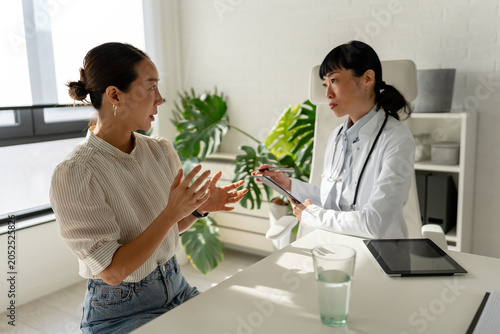 Professional physician explaining health concerns to patient across office desk. Medical guidance, active listening, trust and collaborative healthcare decision making
