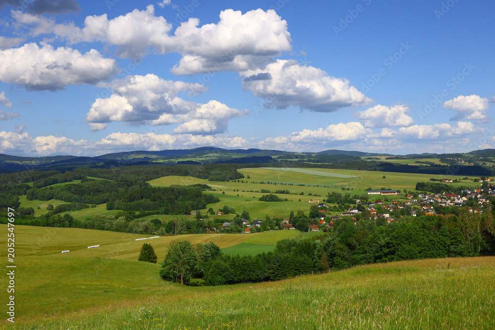 Obraz premium central european foothill landscape in the czech republic with open grassland, clustered village structures and rolling terrain