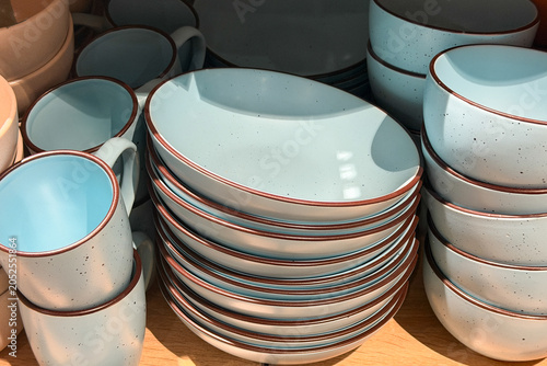 Billede på lærred Light blue speckled ceramic dishes and mugs stacked on display shelf