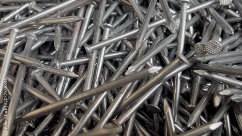 A messy heap of shiny steel wire nails for woodworking. Macrophotography of industrial fasteners and metal hardware equipment 