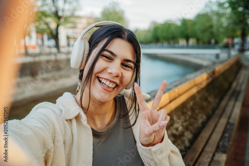 Young woman taking selfie showing peace sign