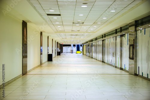 Slika na platnu A long  underground corridor lined with doors undergoing some repairs to an esca