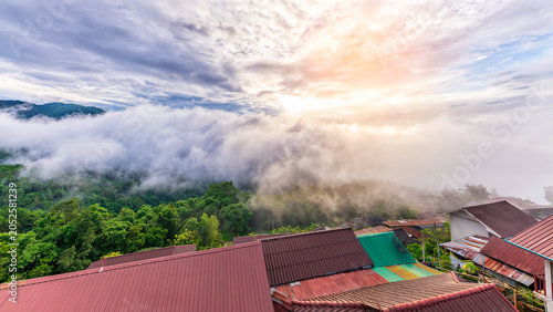 Fotografía Stunning sunrise over Akha Pa Kluay mountain village in Doi Tung, Chiang Rai, Thailand, with a majestic sea of fog covering the green valley and village roofs in the foreground