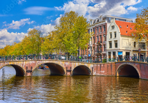 Bridges on the channel in Amsterdam, Netherlands. Dutch houses above river Amstel. Famous landmark in old european city. Sunny day travel photo
