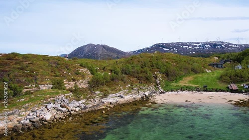 Aerial of small traditional village with greenery covered mountain background, on summer Sommaroy island, Norway