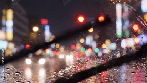 Rainy night city view through wet car windshield