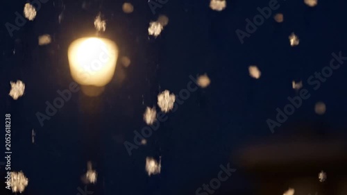 Sparkling snowflakes on window at night with blurred street lamp