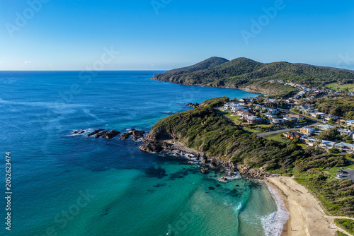 Fotografi Aerial scene capturing One Mile Beach near Forster, NSW, Australia, with a rugged rocky headland in the foreground and Cape Hawke visible in the background