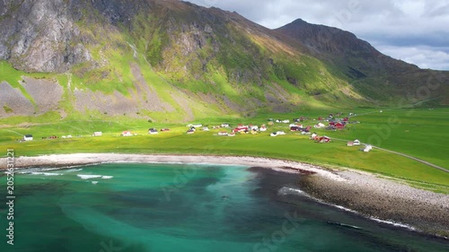 Aerial drone view of Lofoten Islands in Norway, featuring beautiful landscapes on Unstad Beach, white sand, clear water and dramatic mountains near the shore. Experience the natural beauty