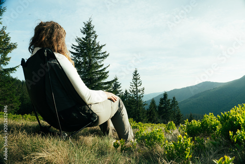 camping in the mountain, woman sit on tourist folding chair a hill overlooking a mountain range, background of mountains, tourism, nature of the Carpathian, vacation, outdoor activities, meditation	