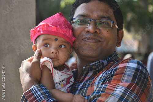 An Indian little girl and father, eyes soft and trusting, portrait. She looks up, curious, with warm, gentle expression. Family, parenting, Fathers day concept.