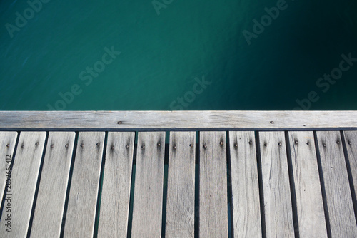 Wooden pier deck over turquoise sea water background.