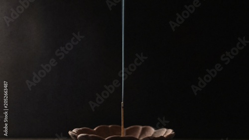 A nearly burned incense stick with a thin, straight line of rising smoke.
