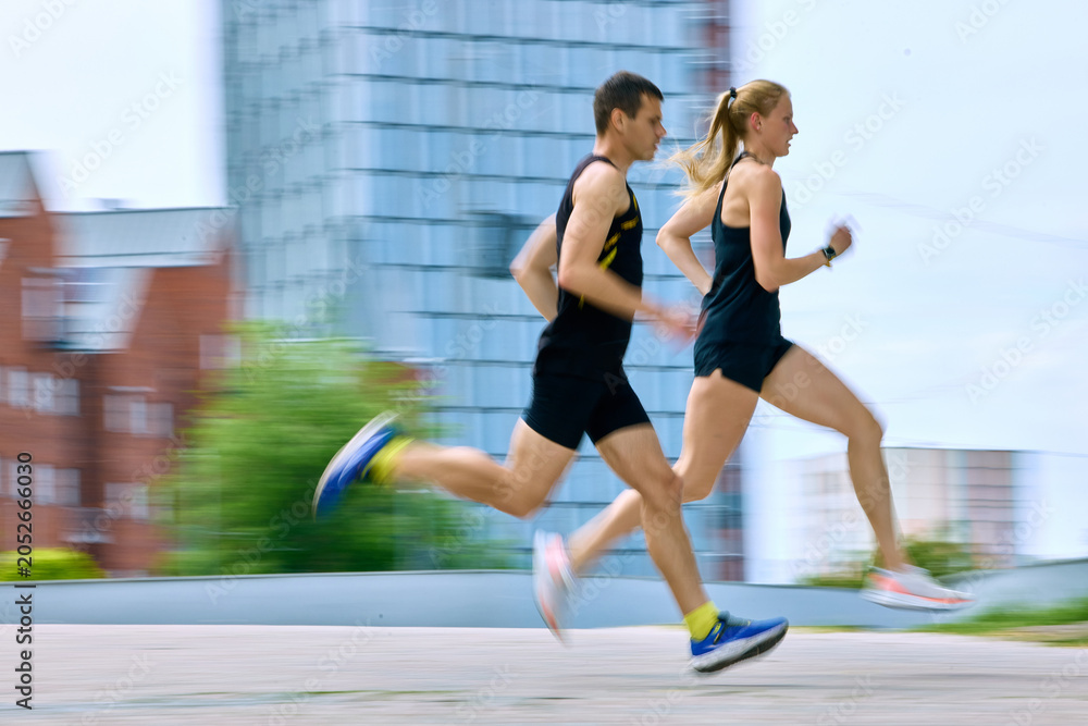 Fototapeta premium Running couple with motion blur in urban fitness training. Concept of speed and motion, performance cardio, running advertising, and dynamic city workout visuals.