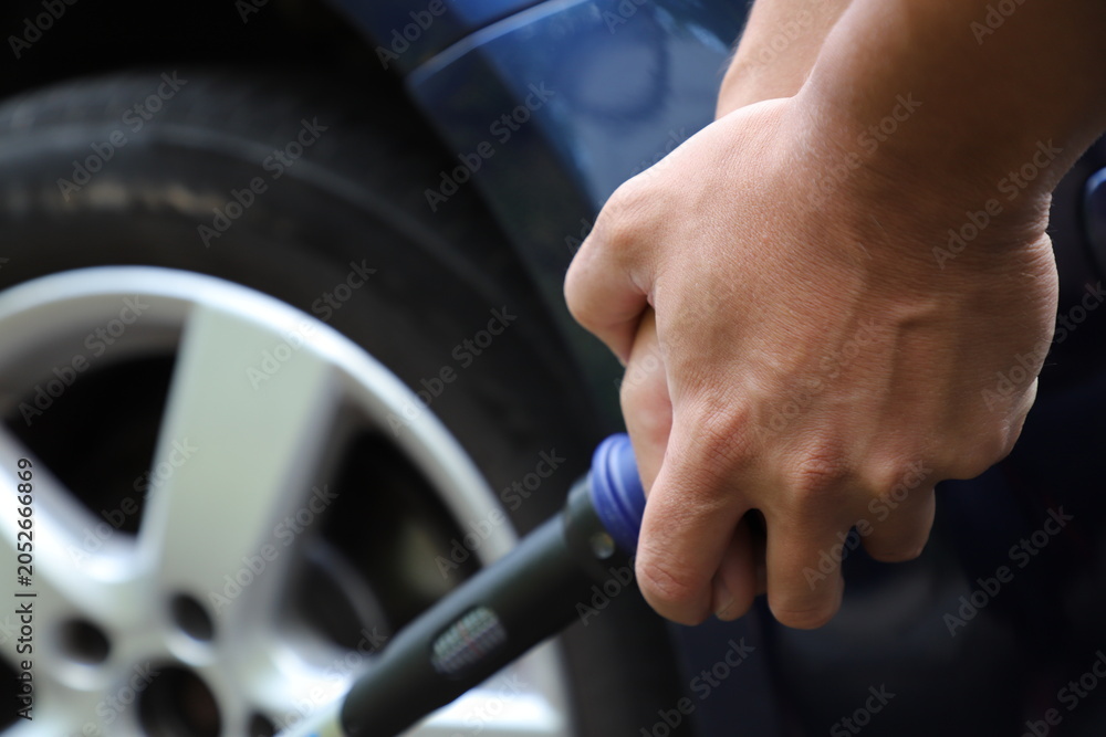 Fototapeta premium Car Wheel Maintenance with Torque Wrench in Close-Up. A mechanic or car owner using a torque wrench to tighten wheel lug nuts on an alloy wheel during vehicle maintenance.