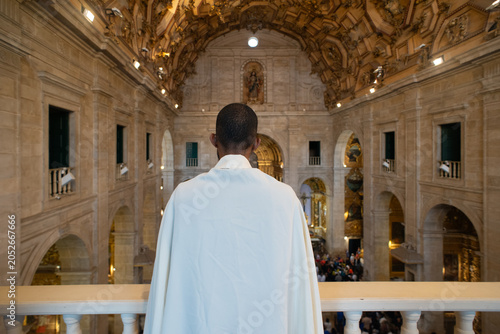 Tableau sur toile Priest with his back to the camera in the choir observing Corpus Christi Mass in