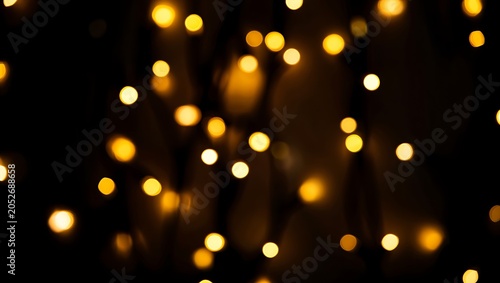 Warm glowing golden bokeh light orbs floating in deep darkness for an elegant festive backdrop with abstract defocused contrast