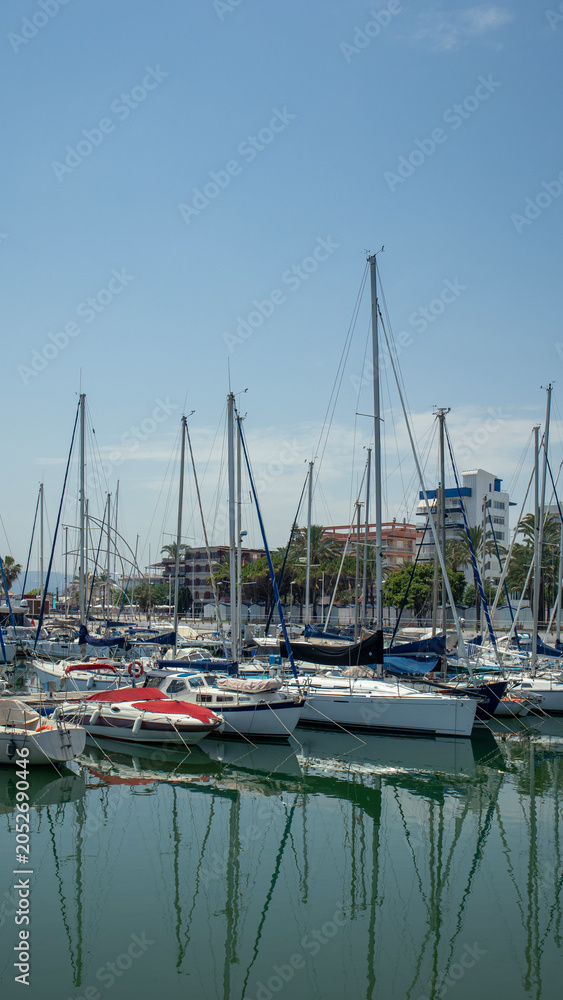 Obraz premium Scenic view of white sailboats and luxury yachts moored in the marina under a clear blue sky on a pleasant summer day