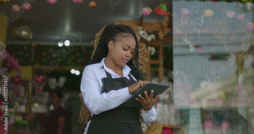Картината върху платно Florist concentrating on digital tablet outside storefront filled with flower bo