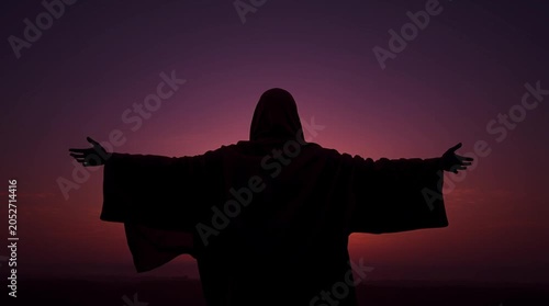 Silhouette of a person with arms outstretched against a vibrant sunset sky