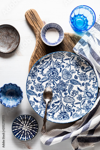 Beautiful blue decorated dishes on and around a wooden board.