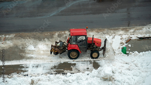 Fotografi Snow removal activity with a red tractor on a winter day in an urban area cleari