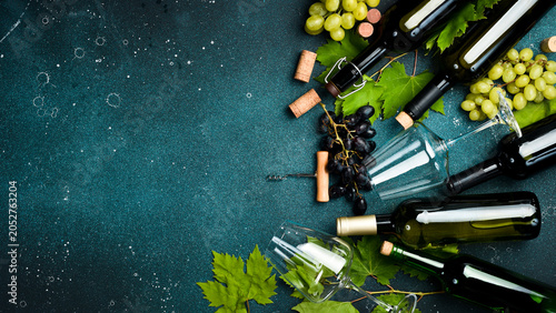 Φωτογραφία Composition of wine bottles, glasses, grapes and grape leaves on a stone table
