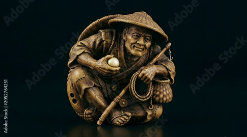 Antique Japanese figure of a smiling farmer holding an egg  