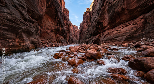 Rushing river water cascading over red rocks inside a steep rocky canyon