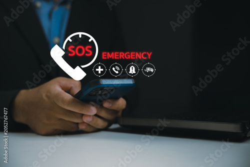 Fotografie A person holding a smartphone with digital SOS emergency icons displayed above, indicating urgent communication or help request