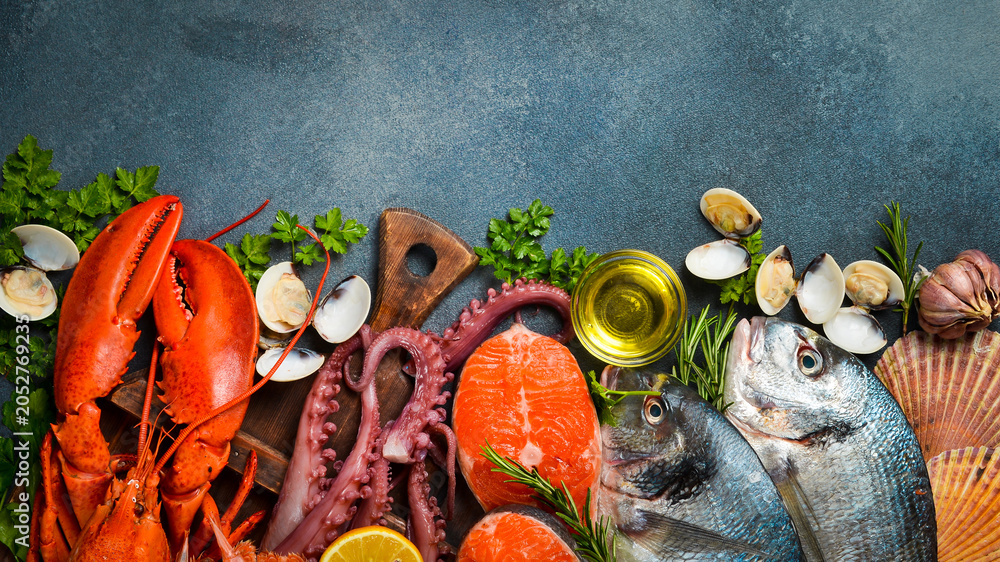 Fototapeta premium Fresh seafood. Wide food banner. Fish, octopus, lobster and other seafood on a gray stone table.