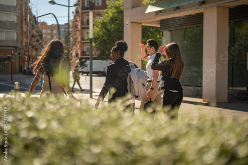 Multicultural business people walking working in sunlit city street