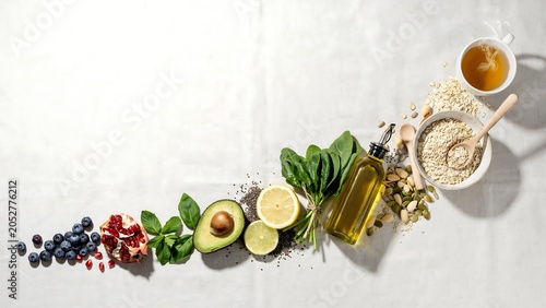 Healthy superfoods and breakfast ingredients arranged in a diagonal line across white background