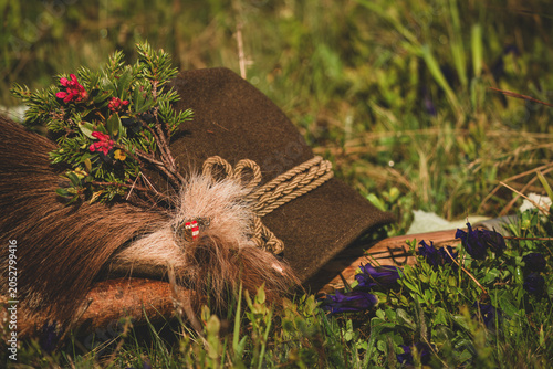 a traditional hunting hat with a chamois beard, a juniper twig and blossoms of alpine rose after the happy hunt, at a sunny spring morning