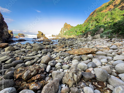 Canvastavla Rocky Shoreline Panorama: A dramatic panorama captures a sun-drenched rocky shoreline with the ocean waves gently lapping against the stones
