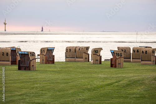 Eine ungeordnete Gruppe von Strandkörben auf einer Wiese am Meer