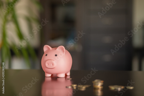 Piggy bank with coins on wooden table at home