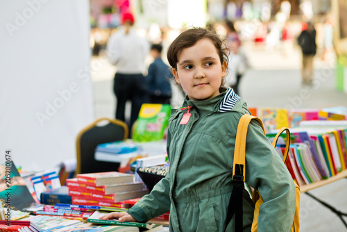 A young girl with a backpack at a book fair