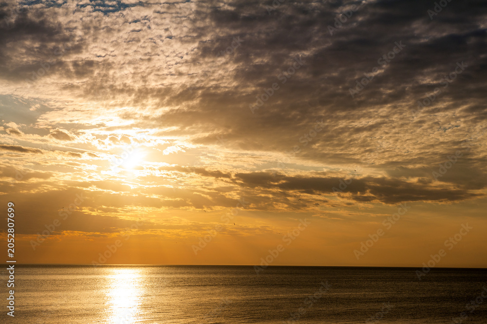 Obraz premium Beautiful sundown background with calm sea and cloudy sky