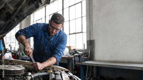 Experienced Auto Mechanic Repairing Classic Car Engine in Workshop