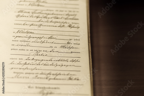 Zbliżenie na stary niemiecki dokument z odręcznym pismem (kurrenta). Detal aktu urzędu stanu cywilnego, płytka głębia ostrości. Vintage tło historyczne, archiwalne i genealogiczne.