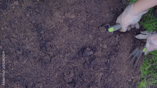 Mixing soil with fertilizer using a hand shovel and a hand fork close up, agriculture. The Video was taken from above.