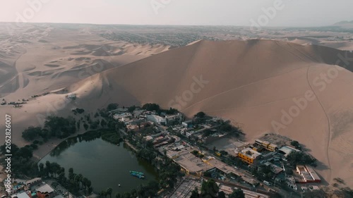 Drone view of Huacachina oasis in Peru, surrounded by towering sand dunes. A unique desert landscape and one of South America’s most famous natural attractions.