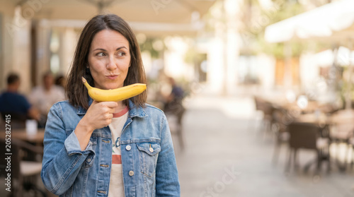 Smiling Woman Holding Banana Like a Toy Gun